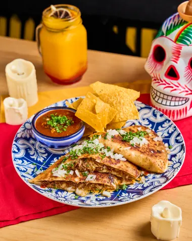 Quesabirrias con consomé y nachos en plato de talavera
